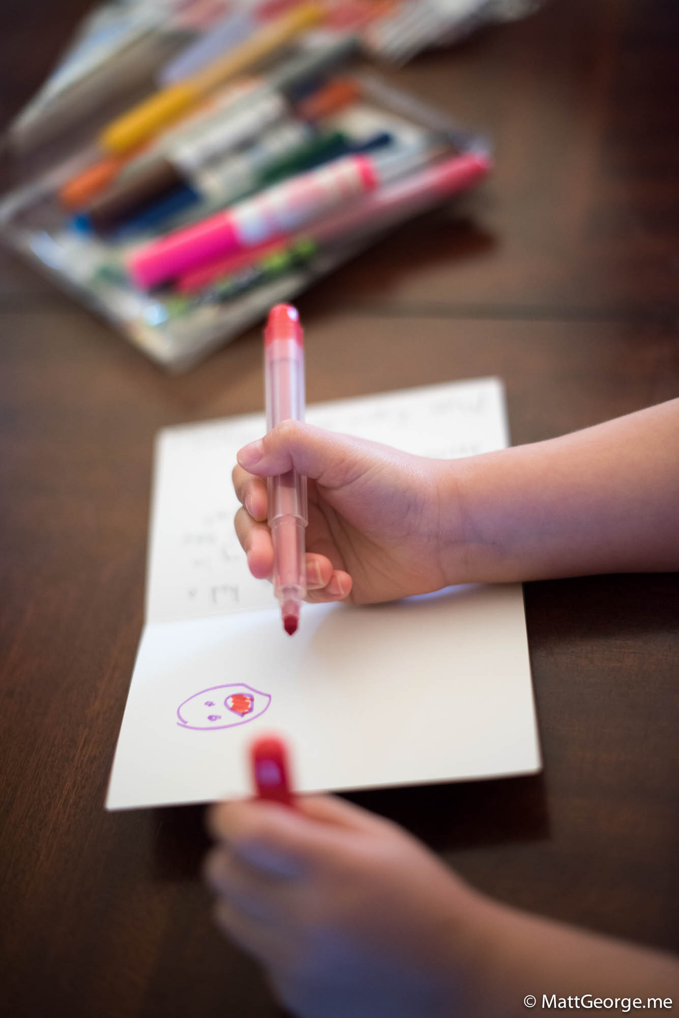 Bella draws a happy face on a card for her teacher.