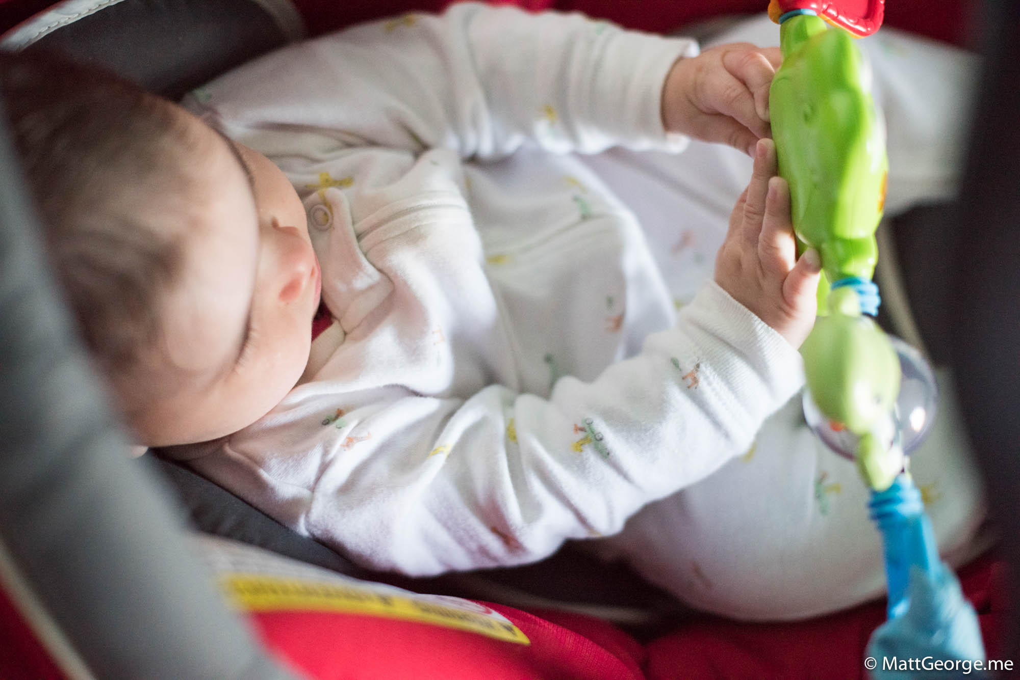 Baby Gianna playing with her toys in her car seat