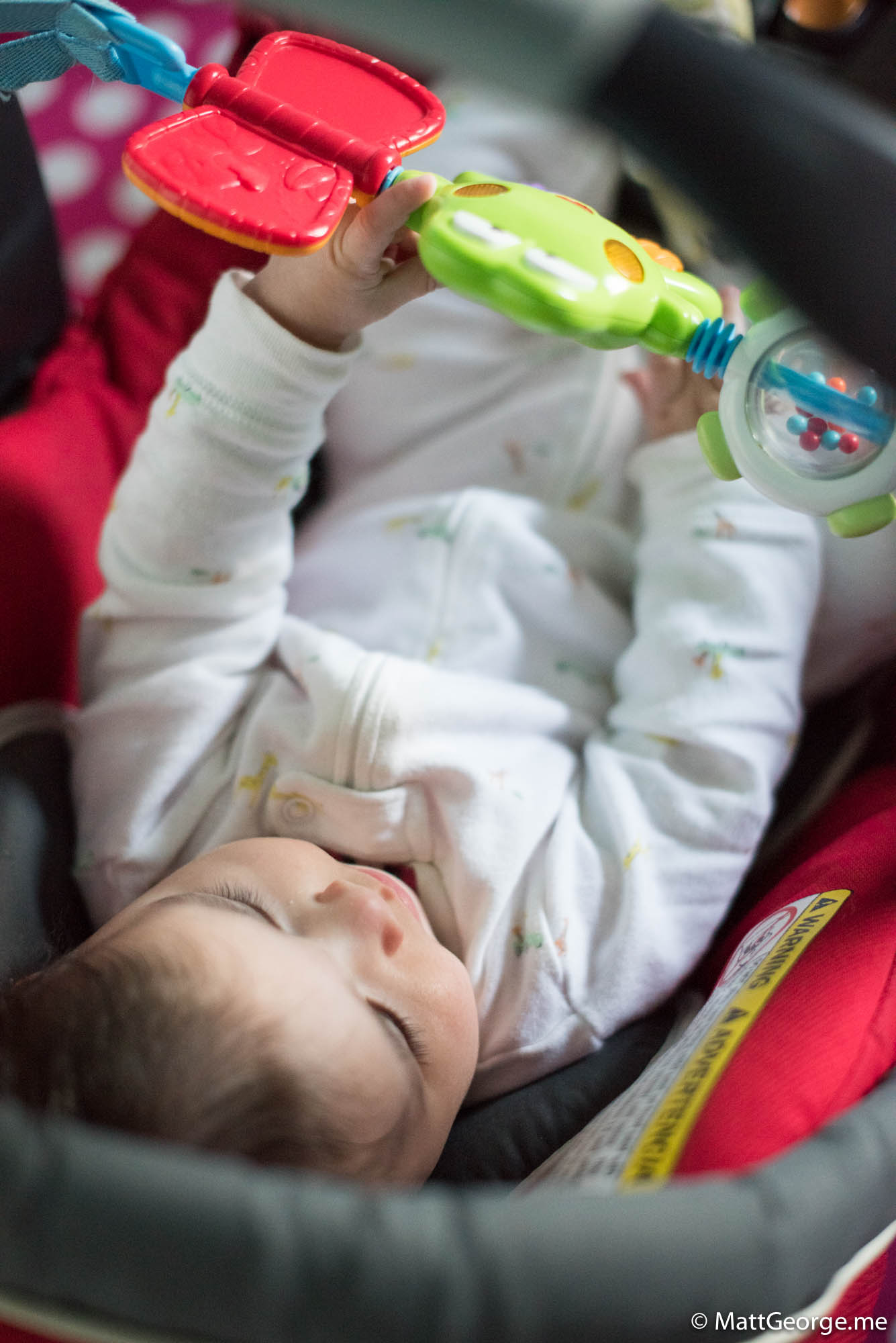 Baby Gianna playing with her toys in her car seat
