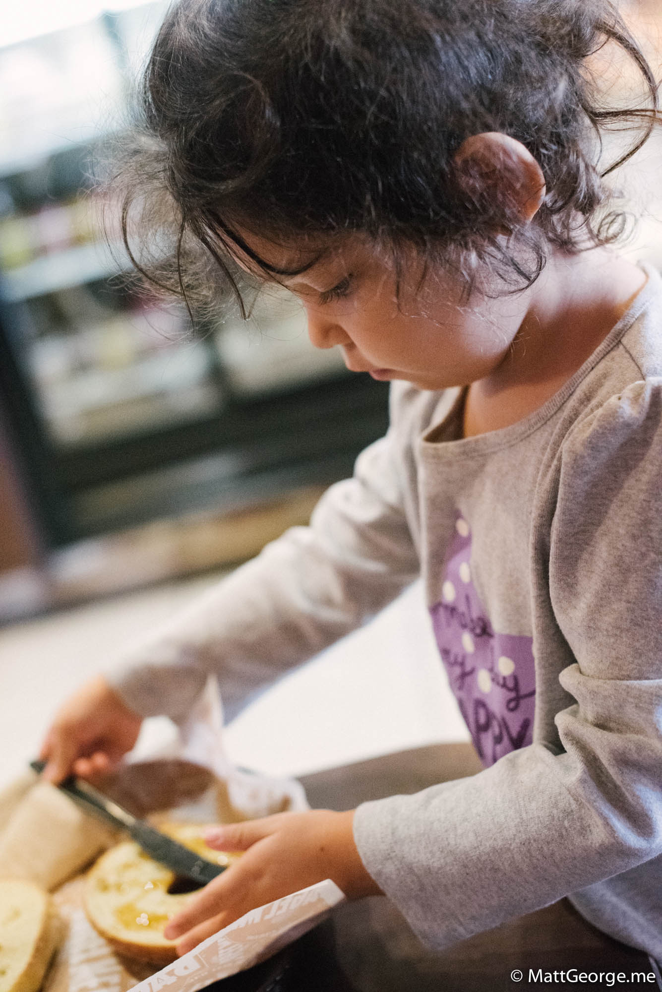 Bella spreading the honey on her bagel