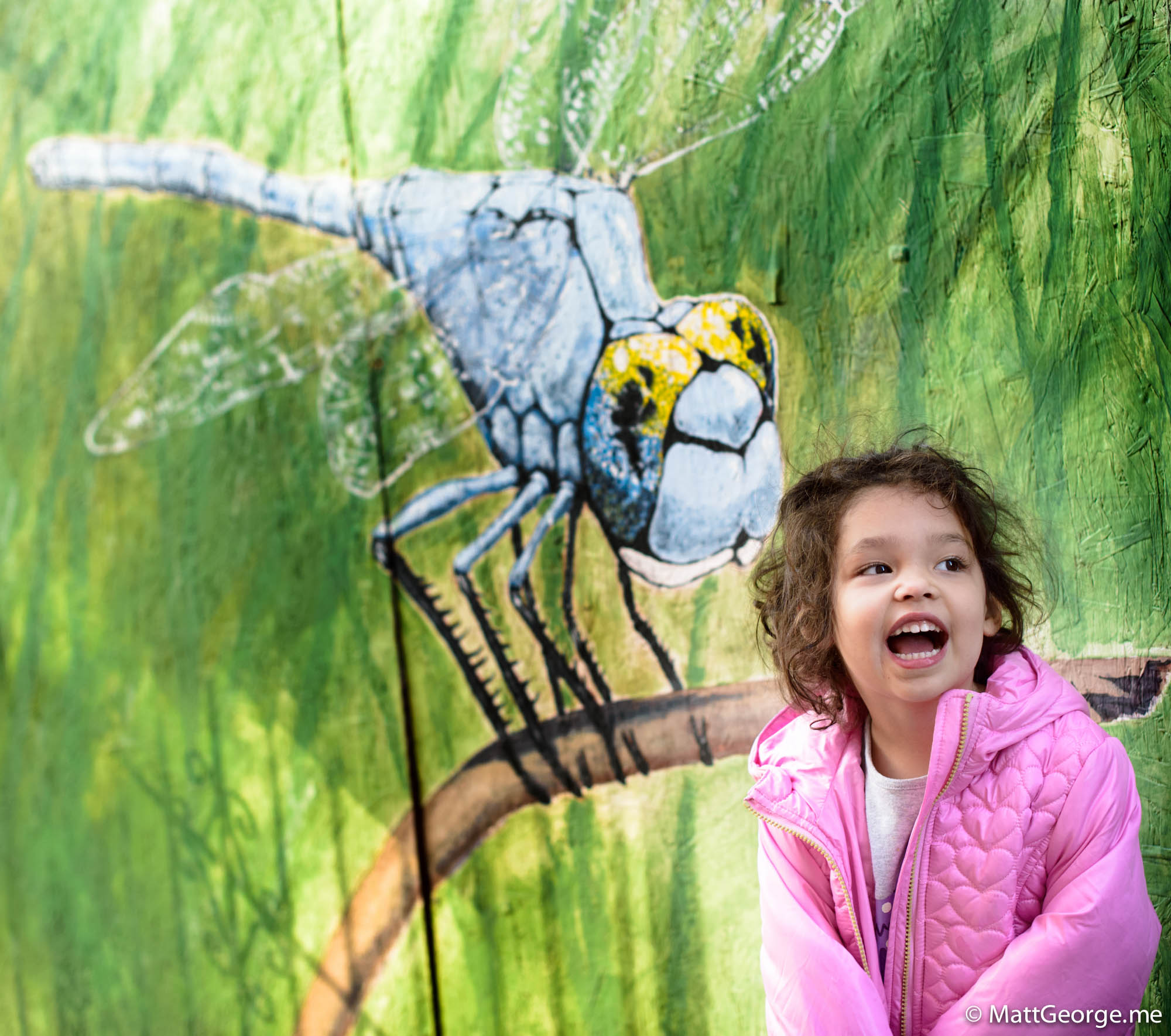 Bella against a dragonfly mural on press wood