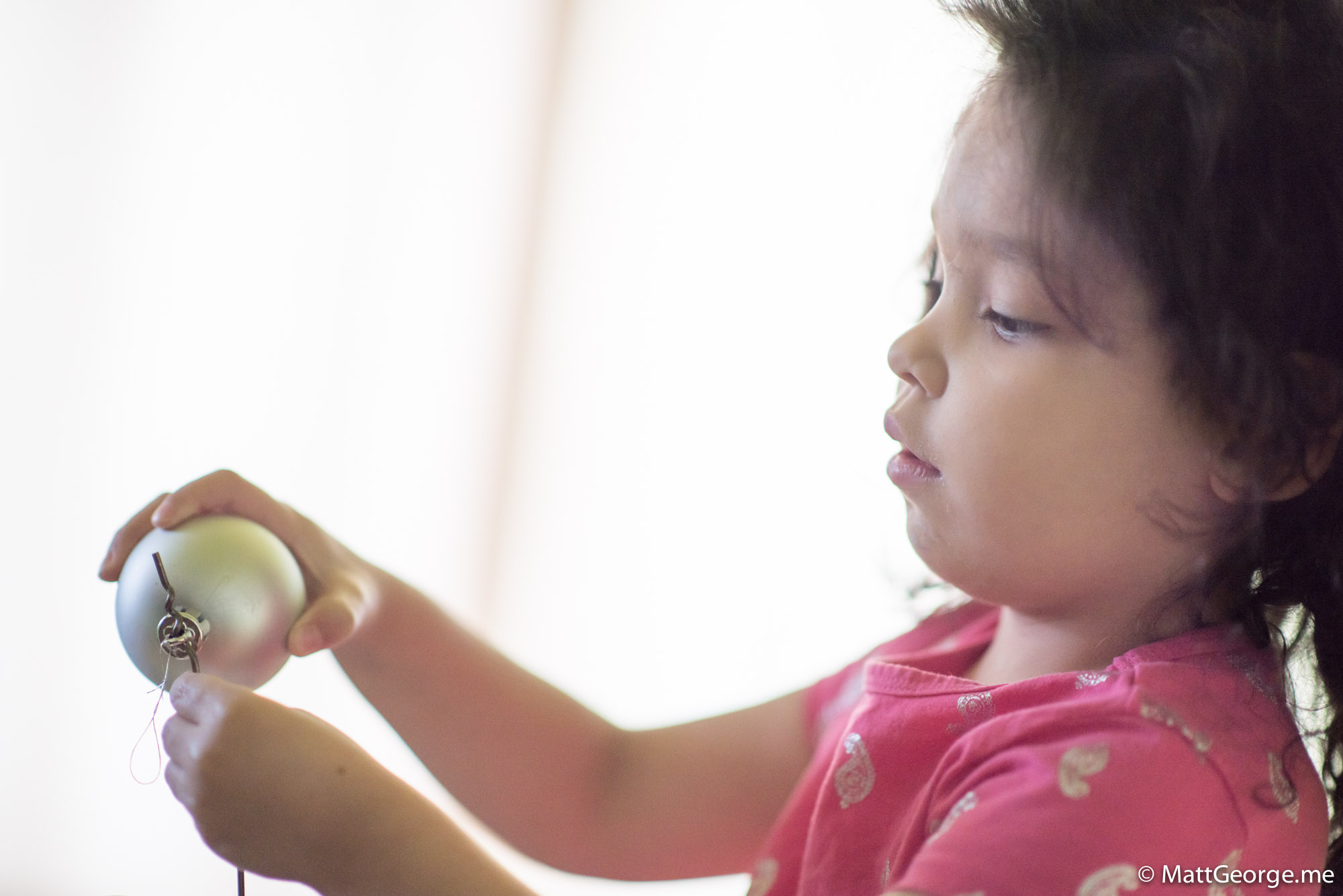 Bella Putting and Ornament Onto the Wire of the Christmas Wreath