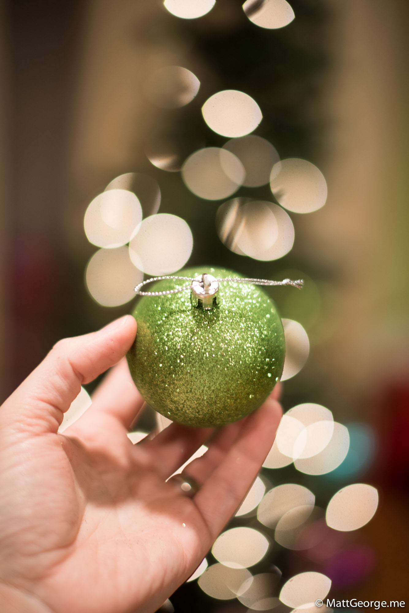 Close-up of Green Christmas Bulb Ornament with White Christmas Lights Bokeh in Background