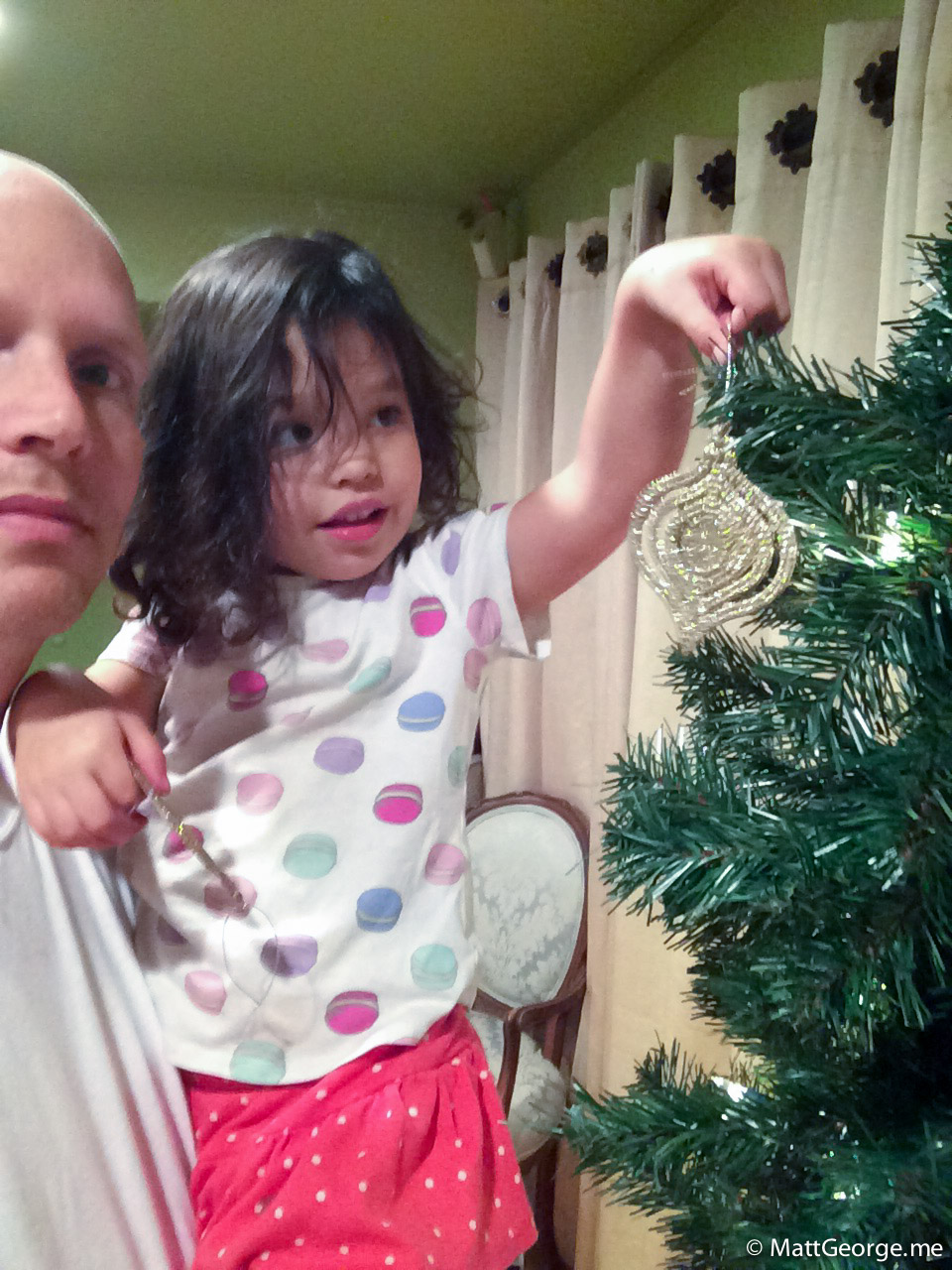 Daddy Holding Bella as She Places a Christmas Ornament Onto Tree