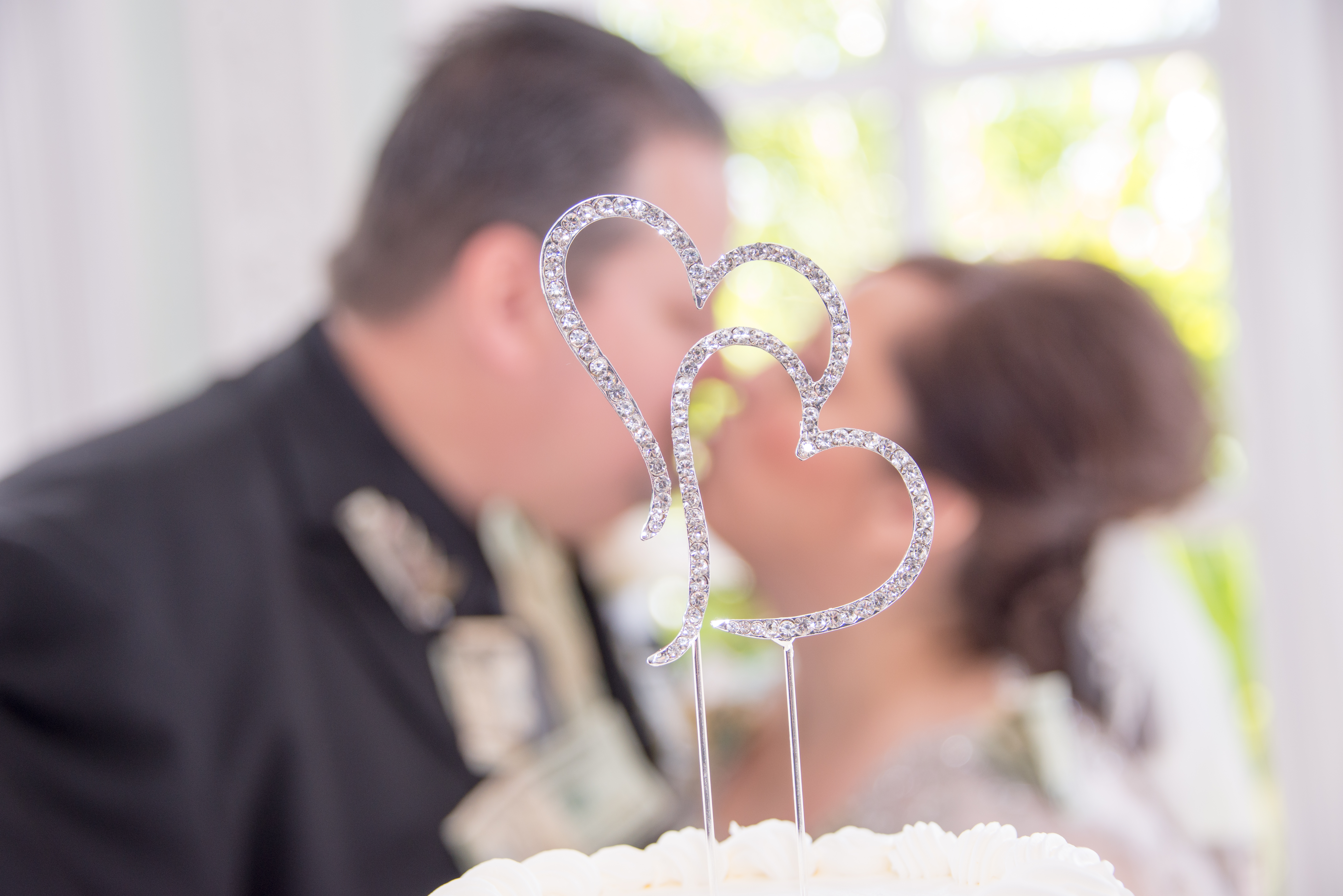 Groom and Bride Out of Focus and Kissing Behind Cake Top